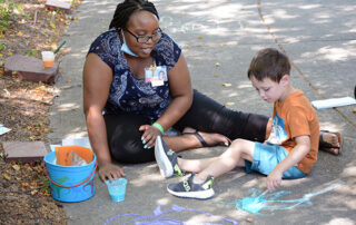 boy and adult painting with sidewalk paint